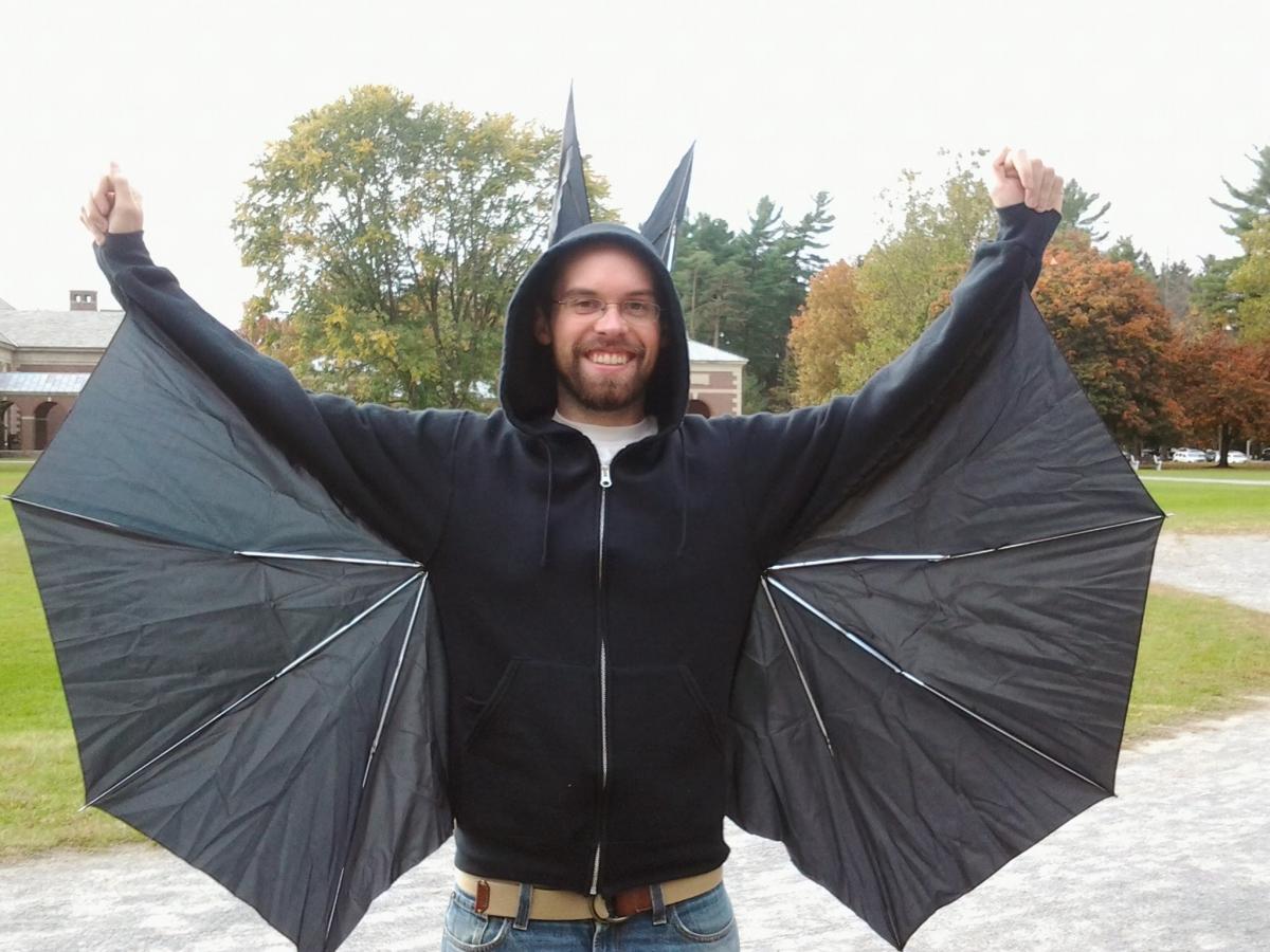 Adam in a bat costume with wings made from a repurposed broken umbrella.