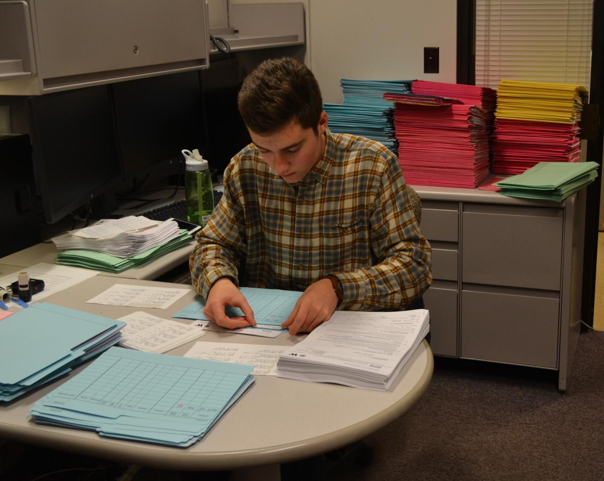 A student works to assemble printed UW admission packets.