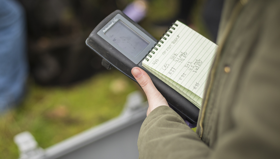 close up of a hand holding a notebook and monitoring device
